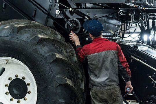 Technician working under tractor with parts on bench
