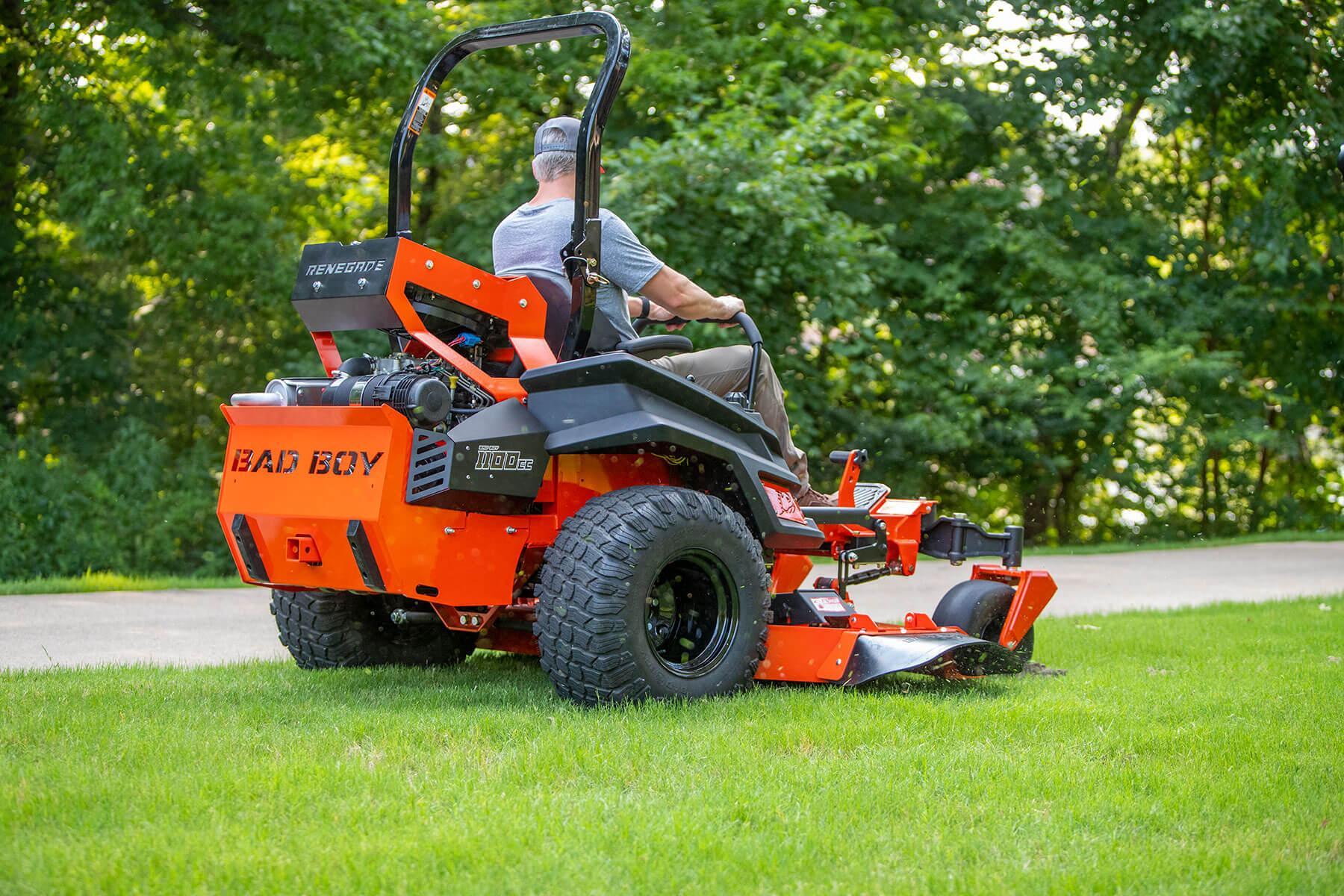 A person sitting on a bad boy mower and mowing the grass
